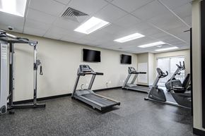 Washington apartment for rent - A gym with treadmills, elliptical machines, and a television.