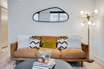 Minneapolis apartment for rent - A living room with a brown couch and a round mirror on the wall.
