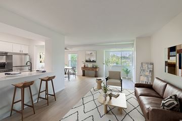 Wayzata apartment for rent - A modern living room with a brown leather couch and a white kitchen area.