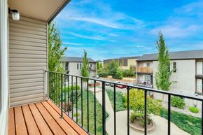 Tualatin apartment for rent - A balcony with a wooden floor overlooks a courtyard with a small tree and a building in the background. at River Lofts Apartments, Oregon