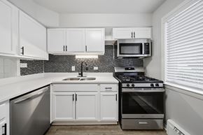 North Aurora apartment for rent - A kitchen with white cabinets and a black and white tiled backsplash.