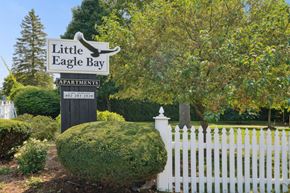 Burlington apartment for rent - A sign for Little Eagle Bay Apartments stands in front of a white picket fence.