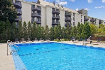 Wheaton apartment for rent - A swimming pool in front of a building with trees in the background.