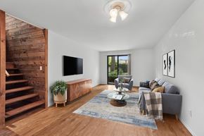 Burlington apartment for rent - A living room with a grey couch, a wooden staircase, and a flat screen TV.