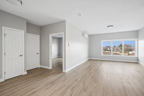 Stratford apartment for rent - A spacious room with wooden flooring and a large window.