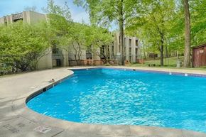 Wayzata apartment for rent - A swimming pool surrounded by trees and an apartment building in the background.