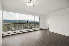 North Vancouver apartment for rent - A large empty room with a view of the mountains outside the window.