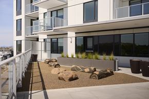 Vancouver apartment for rent - A modern building with a balcony and a landscaped area in front.