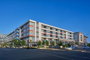 Richmond apartment for rent - A modern multi-story building with a parking lot in front.