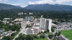 North Vancouver apartment for rent - A cityscape with a large building in the center and mountains in the background.