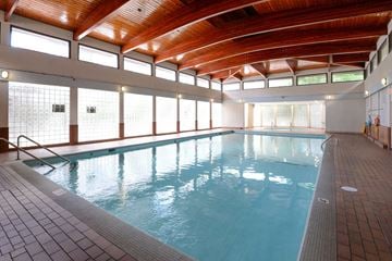 Vancouver apartment for rent - A large indoor swimming pool with a wooden ceiling and tiled floor.