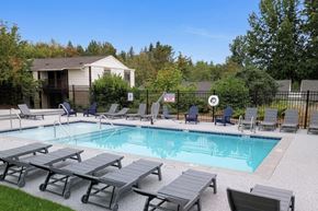 Puyallup apartment for rent - A pool surrounded by lounge chairs and a fence.