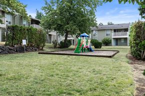 Puyallup apartment for rent - A playground with a slide and a green swing set.