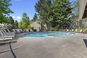 Federal Way apartment for rent - A large outdoor swimming pool surrounded by lounge chairs and trees.