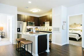 Greenville apartment for rent - A kitchen with a black refrigerator and brown bar stools.