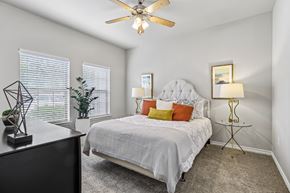 San Antonio apartment for rent - A bedroom with a bed, a ceiling fan, and a nightstand with a lamp.