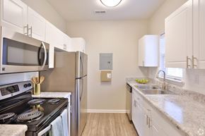 Charlotte apartment for rent - A kitchen with white cabinets and a black stove top.