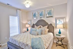 Charlotte apartment for rent - A bedroom with a large bed and a small table with a lamp on it.
