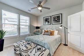 San Antonio apartment for rent - Dog-Friendly Luxury Apartments in North San Antonio, TX - Hardy Oak - Bedroom With Large Windows, Ceiling Fan, Ottomans, Lamps, Wall Art, and Modern Decor.