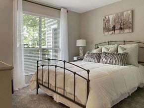 Raleigh apartment for rent - A bedroom with a large bed and a painting on the wall.