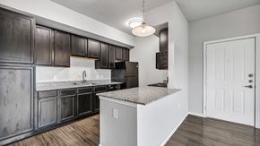 Kerrville apartment for rent - an empty kitchen with dark cabinets and granite counter tops