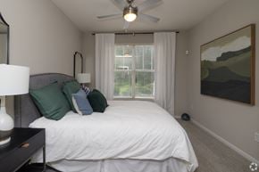 Greenville apartment for rent - A bedroom with a bed, a ceiling fan, and a painting on the wall.