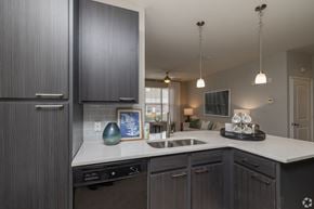 Greenville apartment for rent - A kitchen with dark wood cabinets and a white countertop.