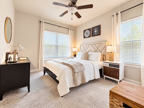 San Antonio apartment for rent - A bedroom with a large bed, a dresser, and a ceiling fan.