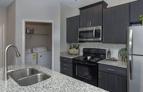 Raleigh apartment for rent - Seasons at Umstead apartments in Raleigh interior kitchen renovated appliances with view into washer dryer closet