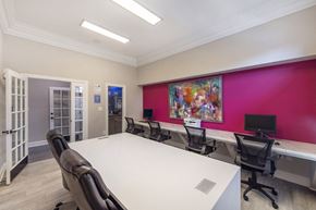 Charlotte apartment for rent - A conference room with a white table and chairs, a pink wall, and a painting on the wall.