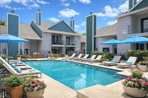 San Antonio townhouse for rent - A pool surrounded by lounge chairs and umbrellas in front of a building.