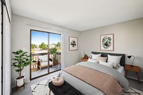 Castle Rock apartment for rent - A bedroom with a large bed and a view of a balcony with furniture.