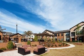 Greenville apartment for rent - A modern building with a brick facade and a landscaped courtyard with a bench and a lamp post.