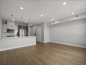 Somerville apartment for rent - A spacious room with wooden flooring and a kitchen area with stainless steel appliances.