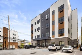 Newark apartment for rent - a tall apartment building with cars parked in front of it