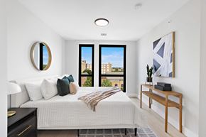 Newark apartment for rent - a bedroom with a large bed and a wooden desk with a potted plant