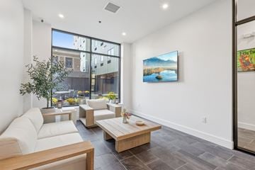Newark apartment for rent - A living room with a white couch and a painting of a lake on the wall.