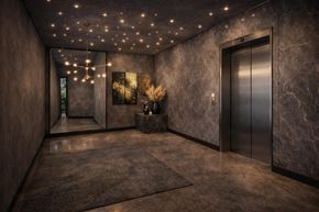 Newark apartment for rent - A hallway with a marble floor and walls, a carpeted area, and a wall-mounted elevator.
