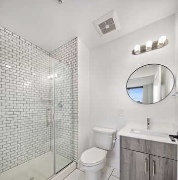 Newark apartment for rent - A white toilet sits next to a sink in a bathroom with a glass shower stall.