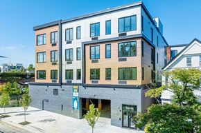 Newark apartment for rent - A modern multi-story building with a parking lot in front.