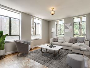 Baltimore apartment for rent - A modern living room with a grey sofa, a grey armchair, a wooden coffee table, and a grey ottoman.