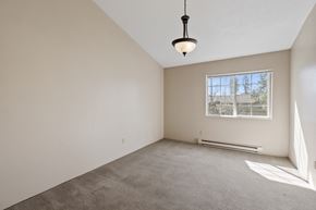 Spokane apartment for rent - empty room with carpet, white walls, chandelier in center, and window.