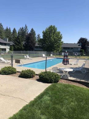 Spokane apartment for rent - a pool in a backyard with a table and chairs