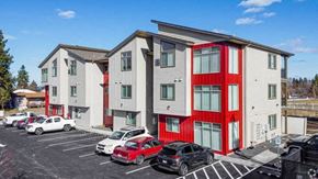 Post Falls apartment for rent - A parking lot with cars and a building with red trim.