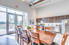 Spokane apartment for rent - A dining room with a wooden table and chairs, a fridge, and a window with a view of the outdoors.