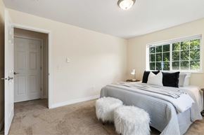 Spokane apartment for rent - A bedroom with a bed, two stools, and a window.