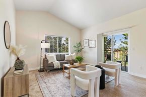 Spokane apartment for rent - A living room with a grey couch, a wooden coffee table, and a large window.