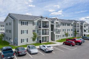 Spokane Valley apartment for rent - A parking lot in front of a grey apartment building with cars parked in the lot.