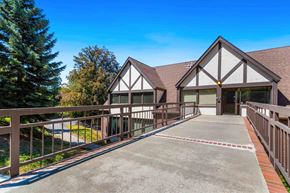 Spokane apartment for rent - A house with a brown roof and white walls has a driveway leading to the front door.