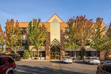Spokane apartment for rent - A building with a large glass entrance and a green tree in front.